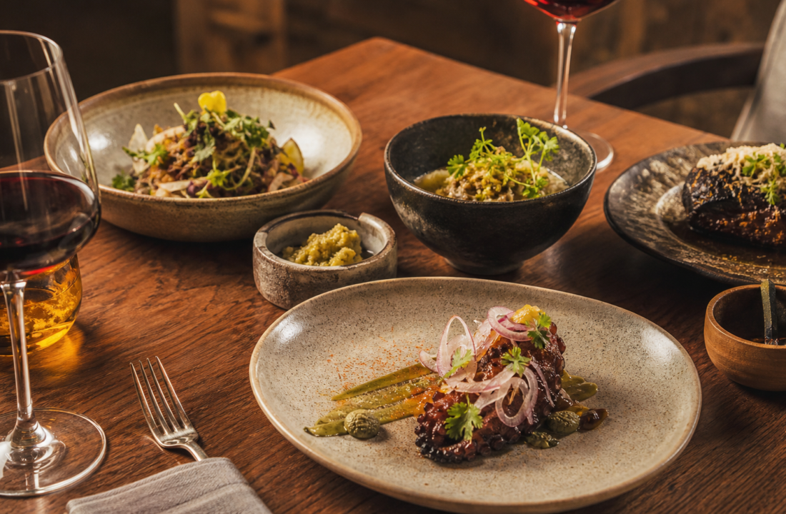 Platillos mexicanos contemporáneos y copas de vino en una mesa de experiencia gastronómica.